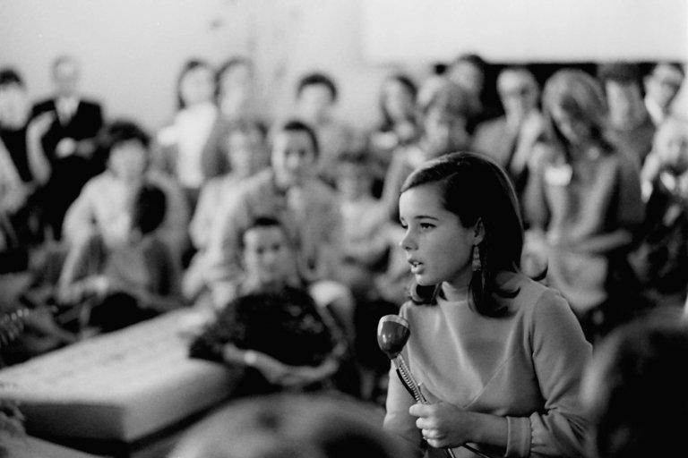 A student speaks in a microphone in a classroom during parents day in 1967